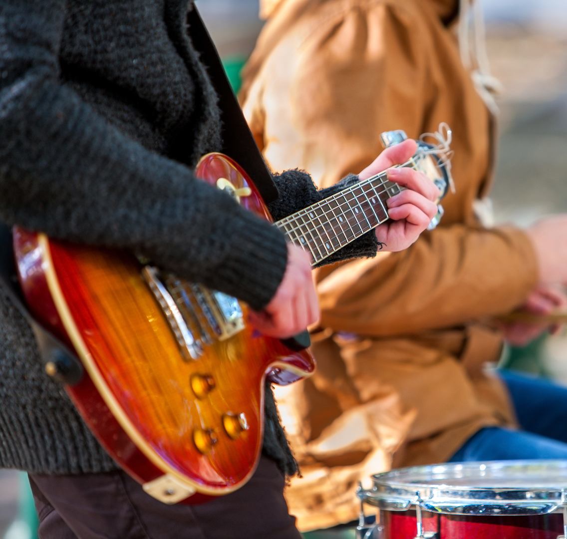 Een muzikant die buiten elektrische gitaar speelt.